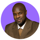 Headshot of a person with a beard in a brown suit, set against a purple circular background.