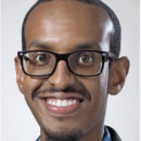 A headshot of a person wearing glasses and smiling.