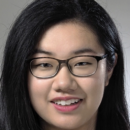 Headshot of a person with long black hair and glasses, smiling.