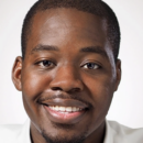 Portrait of a smiling person wearing a white shirt against a neutral background.