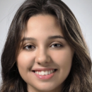 Headshot of a person with long dark hair and a friendly smile, set against a neutral background.