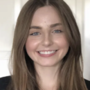 Headshot of a person with long brown hair smiling against a neutral background.