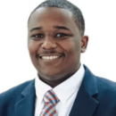 Headshot of a person in a blue suit, white shirt, and patterned tie, smiling against a white background.