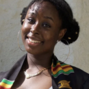 A smiling person wearing a colorful striped scarf and hoop earrings, possibly representing cultural pride or celebration.