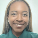 A headshot of a person smiling, wearing a green shirt, with long straight hair and earrings.