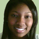 A headshot of a person with long dark hair smiling against a light green background.