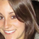 A headshot of a person with long brown hair smiling.