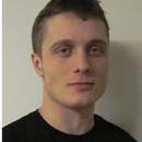 Headshot of a person with short hair, wearing a black shirt, against a neutral background.