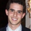 This is a headshot of a person smiling, wearing a suit and tie.