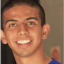 A person smiling, wearing a blue shirt, with a close-cropped haircut, in a headshot.