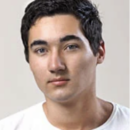 Headshot of a person with short, dark hair, wearing a white shirt, and looking directly at the camera with a neutral expression.