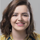 A headshot of a person with short brown hair, smiling, wearing a patterned shirt on a gray background.