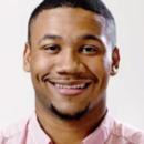 A person smiling in a headshot, wearing a light pink shirt, with short hair and a neatly trimmed beard against a plain background.