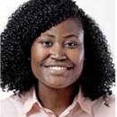 Headshot of a person with curly hair smiling, wearing a light-colored shirt, against a plain background.