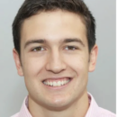 Headshot of a smiling person wearing a light pink collared shirt against a neutral background.