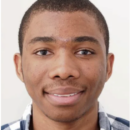 Headshot of a person smiling, wearing a checkered shirt against a plain background.