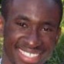 Headshot of a person smiling, with a background of greenery.