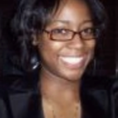 A headshot of a person with dark hair wearing glasses and a dark outfit, smiling at the camera.