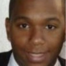 A headshot of a person wearing a suit and tie, with a neutral expression.